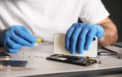 Technician repairing mobile phone at table, closeup