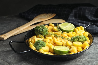 Photo of Raw yellow carrot with limes and broccoli on grey table