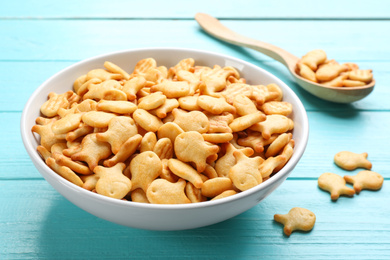Photo of Delicious goldfish crackers in bowl on light blue wooden table