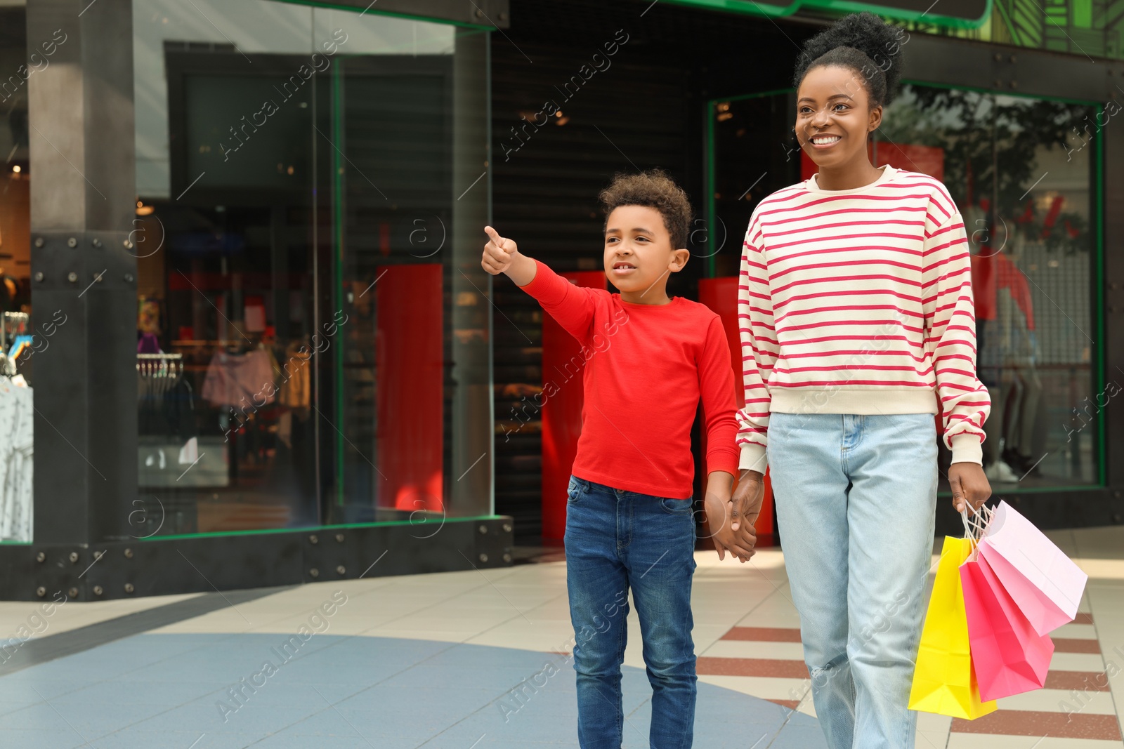 Photo of Family shopping. Happy mother and son with colorful bags in mall