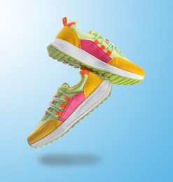 Image of Pair of stylish sneakers in air on color gradient background
