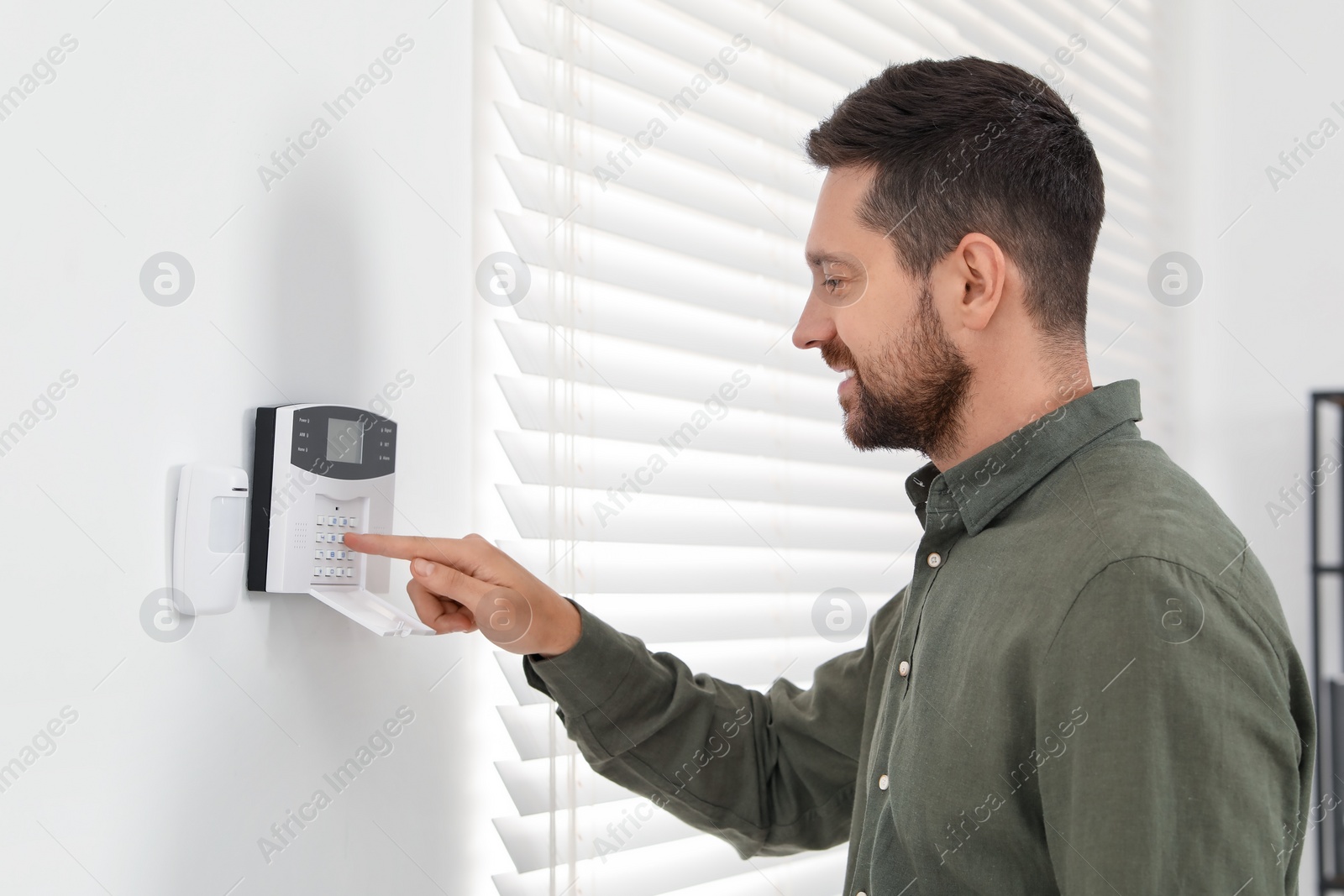 Photo of Man entering code on home security system indoors