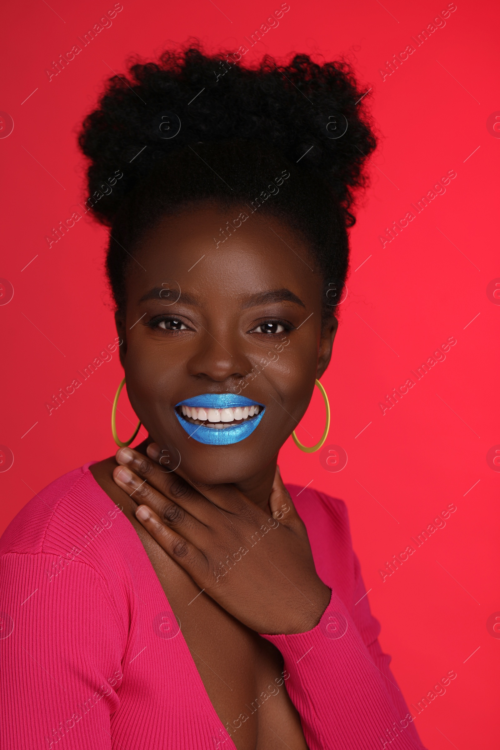 Photo of Fashionable portrait of beautiful happy woman with bright makeup on coral background