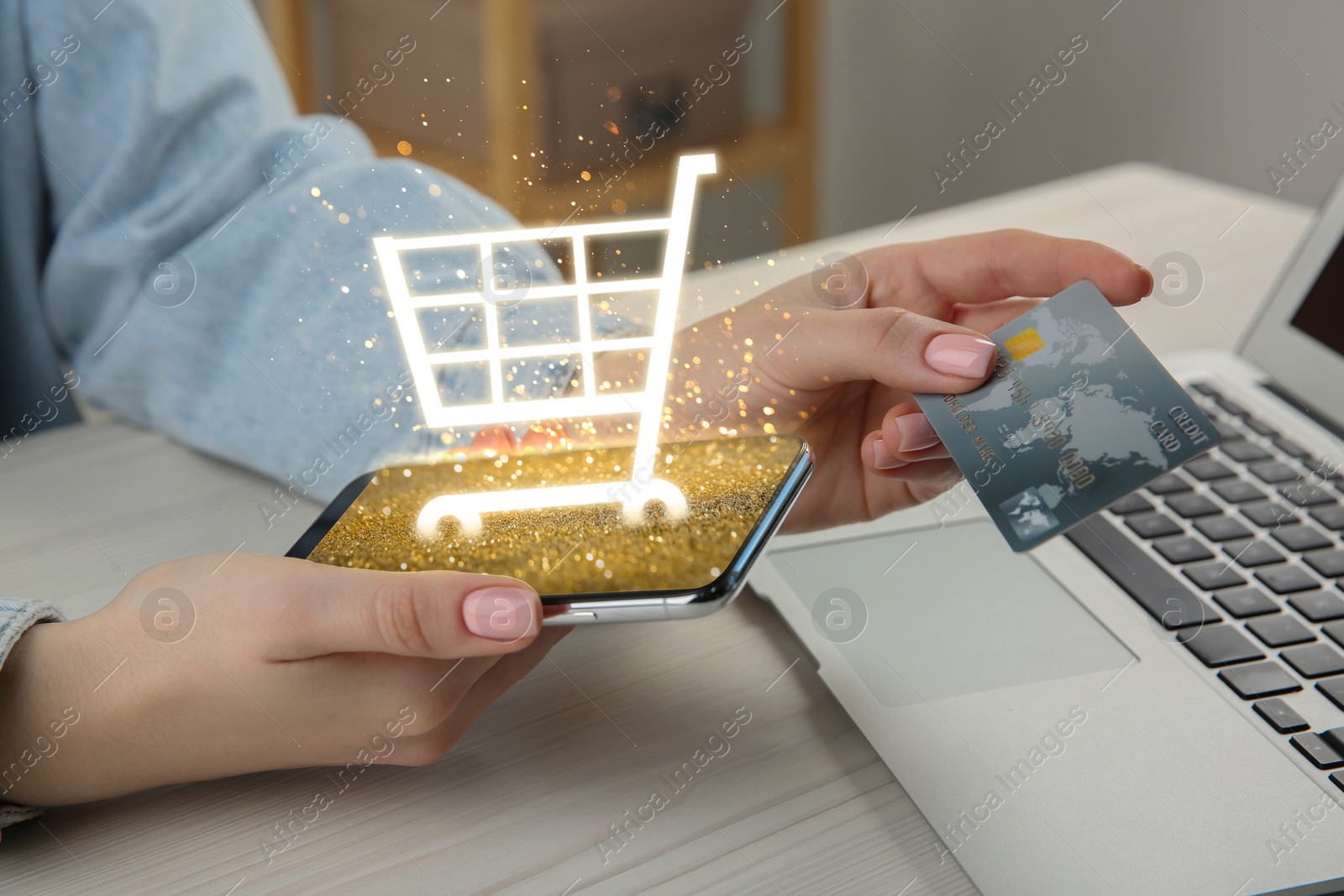 Image of Woman with credit card using smartphone for online purchases at table, closeup. Shopping cart icon over device screen