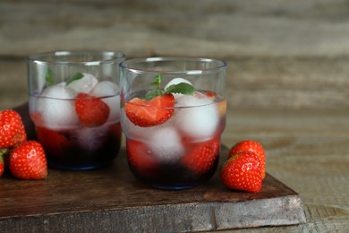 Photo of Delicious cocktails with strawberries, mint and ice balls on wooden table