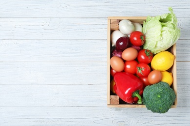 Wooden crate full of fresh products on light background, top view. Space for text