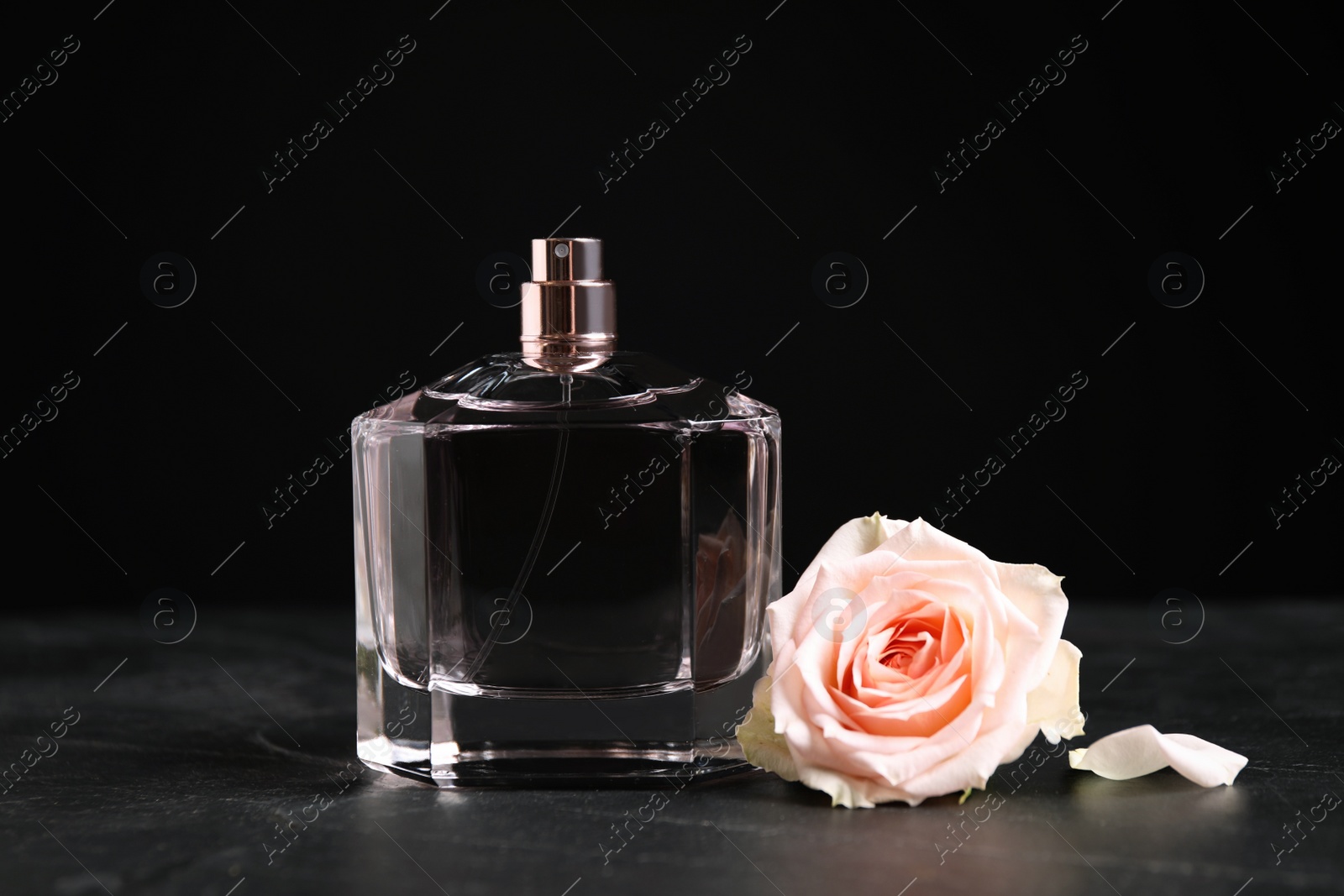 Photo of Bottle of perfume and beautiful rose on black table