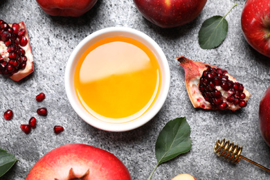 Honey, apples and pomegranates on grey table, flat lay. Rosh Hashanah holiday