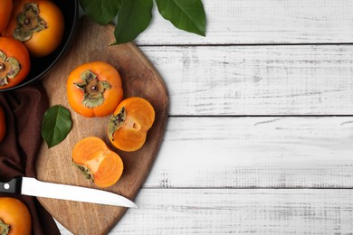 Whole and cut delicious ripe persimmons on white wooden table, flat lay. Space for text