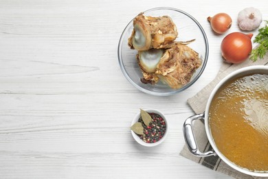 Photo of Delicious homemade bone broth and ingredients on white wooden table, flat lay. Space for text