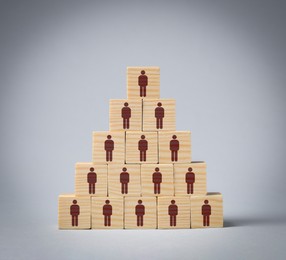 Image of Team and management concept. Pyramid of wooden cubes with human icons on grey background