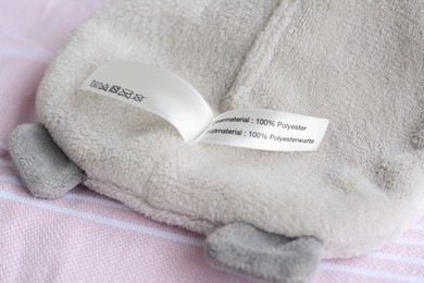 Photo of White clothing label with care information on light gray garment
