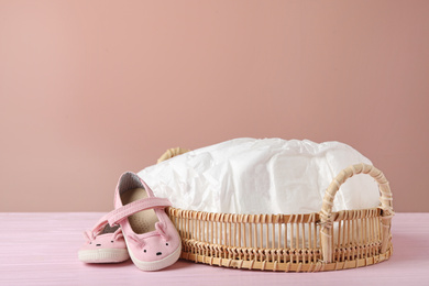 Photo of Tray with baby diapers and child's shoes on wooden table against pink background