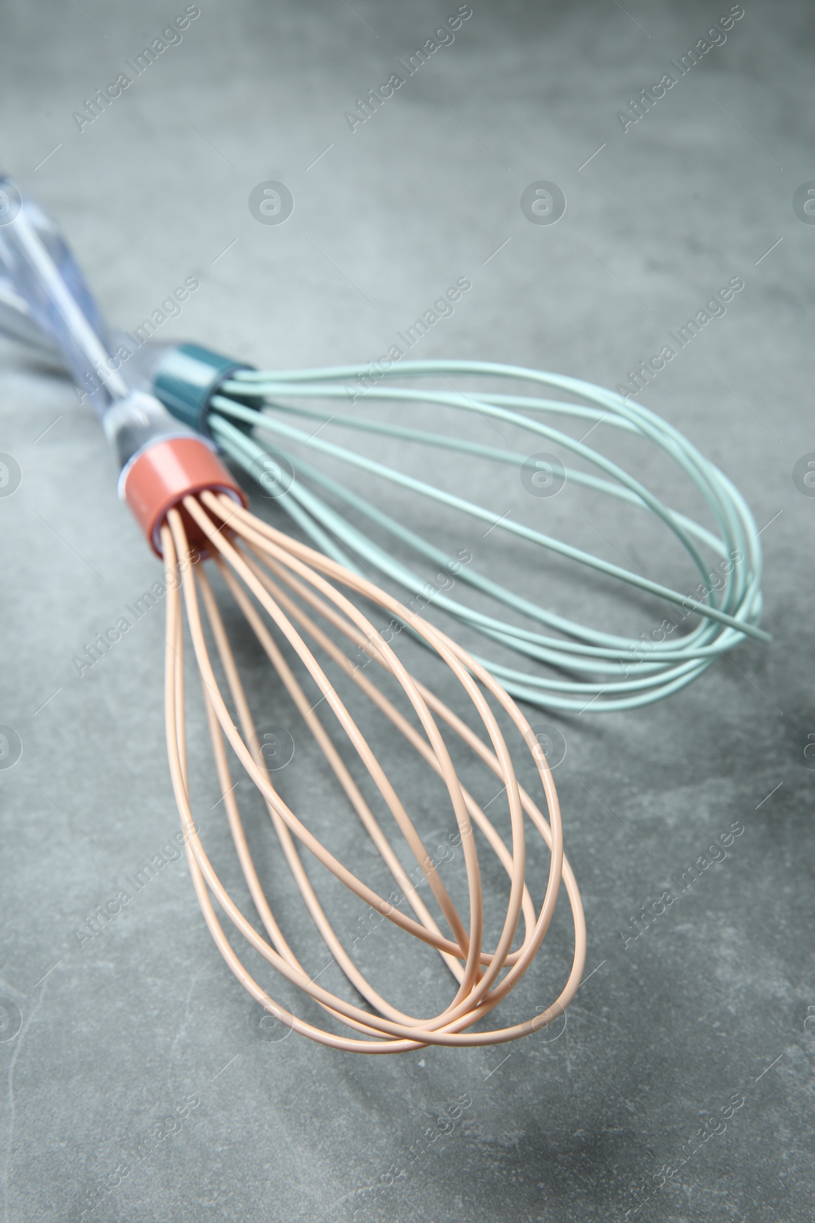 Photo of Two whisks on gray table, closeup. Kitchen tool