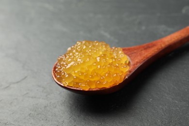 Photo of Fresh pike caviar in spoon on black table, closeup