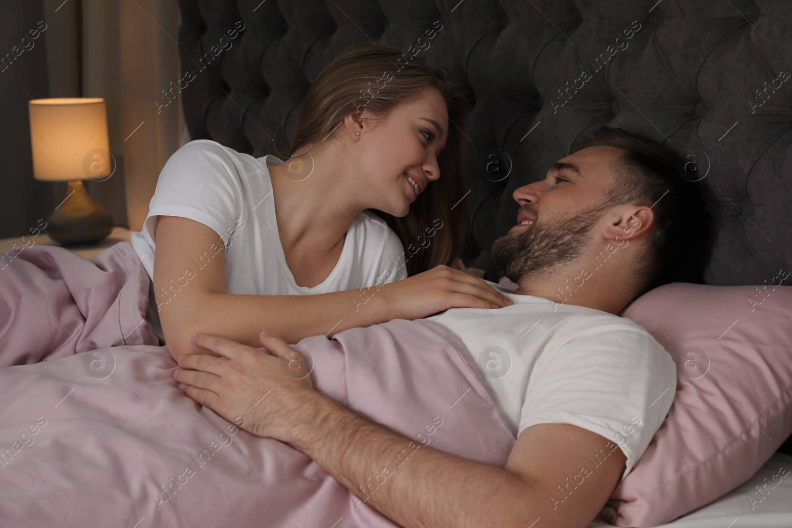 Photo of Young couple together in bed at nighttime