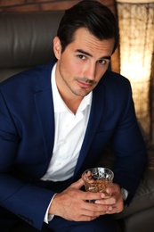 Young man with glass of whiskey indoors