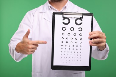 Photo of Ophthalmologist pointing at vision test chart on green background, closeup