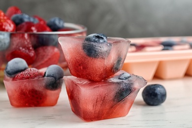 Ice cubes with berries on table, closeup