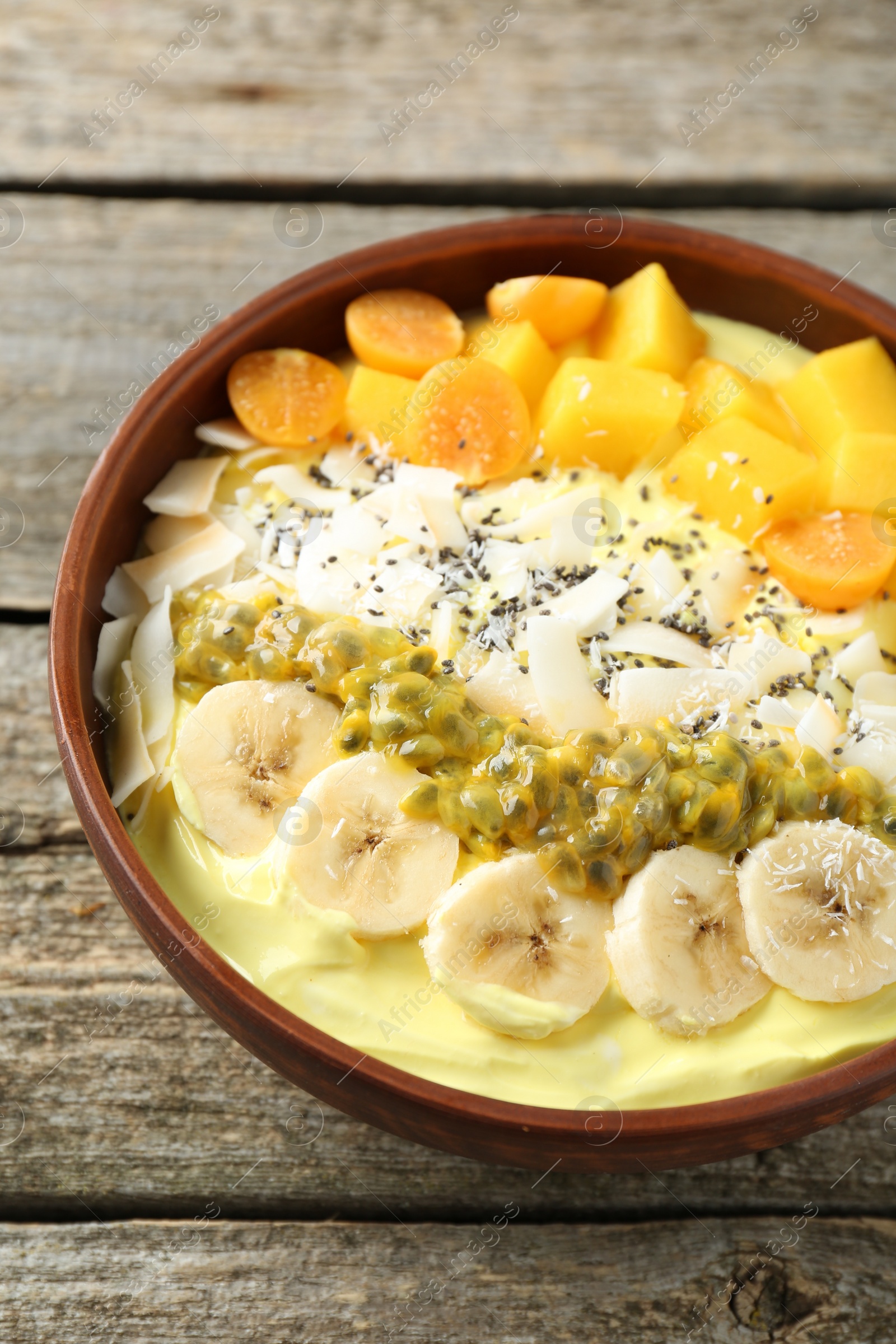 Photo of Tasty smoothie bowl with fresh fruits on wooden table, closeup