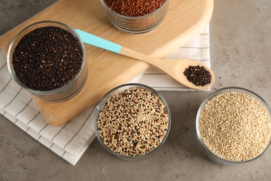 Glasses with different types of quinoa on grey table