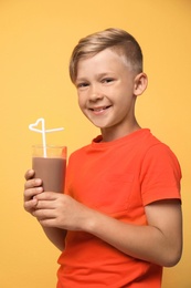 Little boy with glass of milk shake on color background