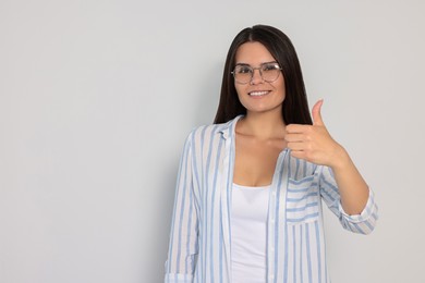 Photo of Young woman showing thumb up on white background, space for text
