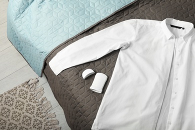 Stick deodorant and white shirt on bed, top view