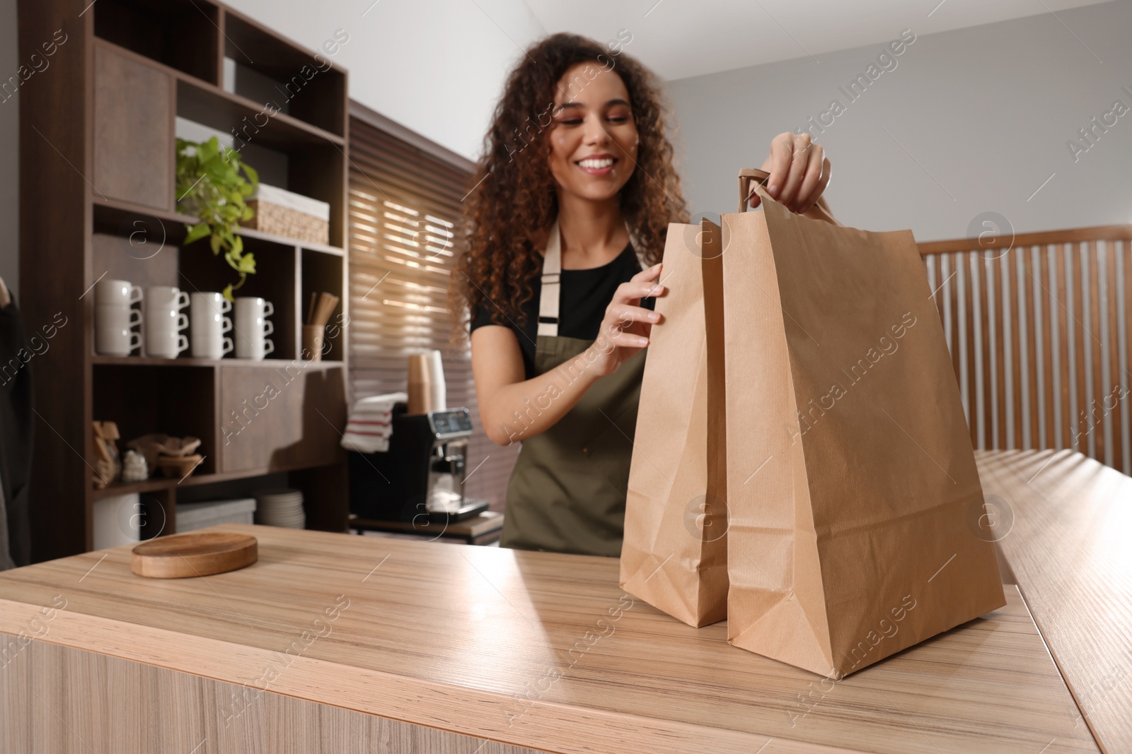 Photo of Worker with paper bags at counter in cafe, focus on hands