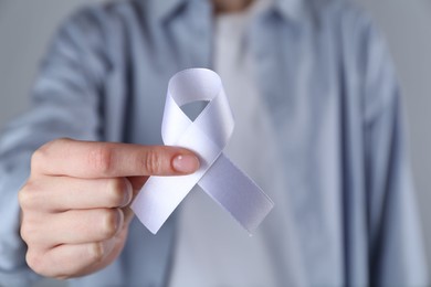 Photo of Woman holding white awareness ribbon, closeup view