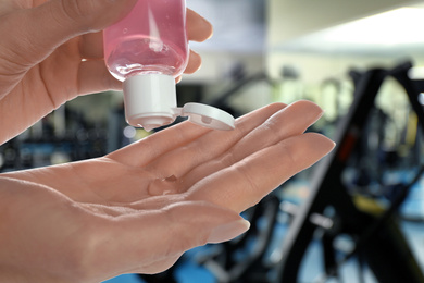 Image of Woman applying antiseptic gel at gym, closeup. Preventive measures during epidemic period 