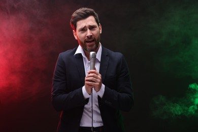 Photo of Emotional man with microphone singing in color lights