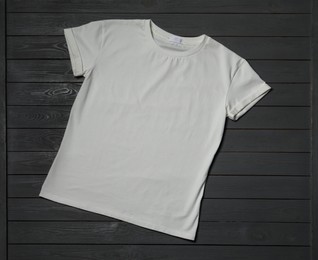 Stylish white T-shirt on gray wooden table, top view