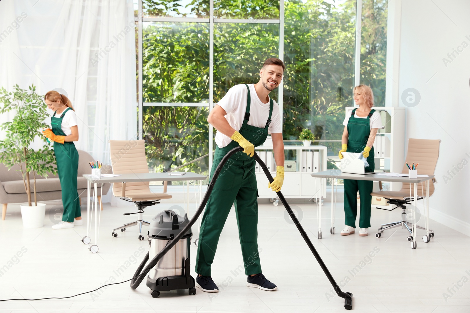 Photo of Team of janitors in uniform cleaning office