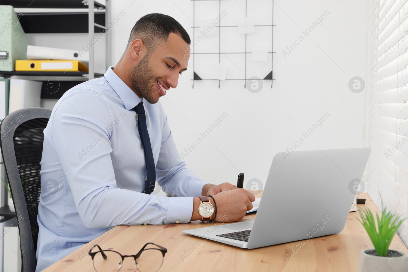 Photo of Happy young intern working at table in modern office