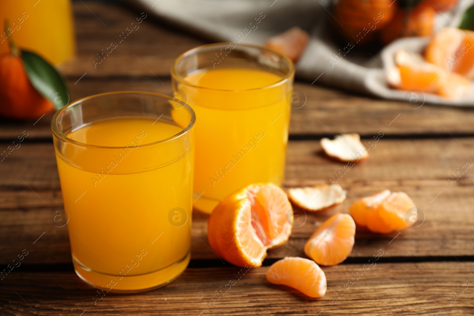 Photo of Glasses of fresh tangerine juice and fruits on wooden table