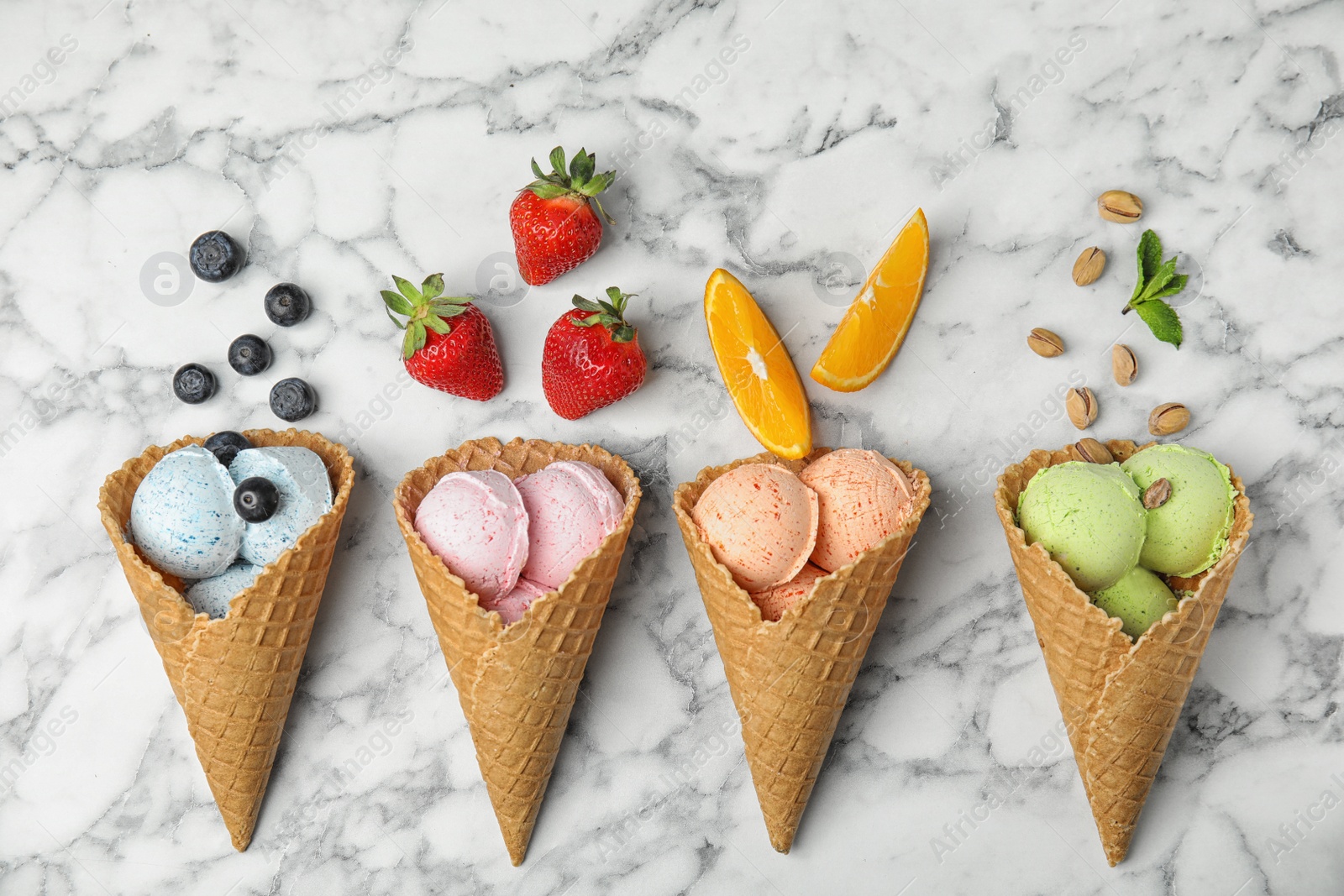 Photo of Flat lay composition with delicious ice creams in waffle cones on marble table