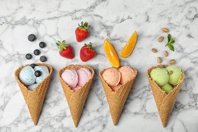 Flat lay composition with delicious ice creams in waffle cones on marble table