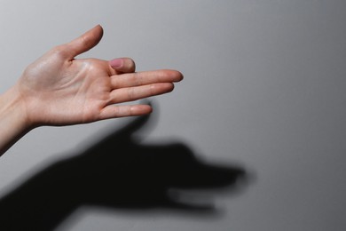 Shadow puppet. Woman making hand gesture like dog on grey background, closeup. Space for text