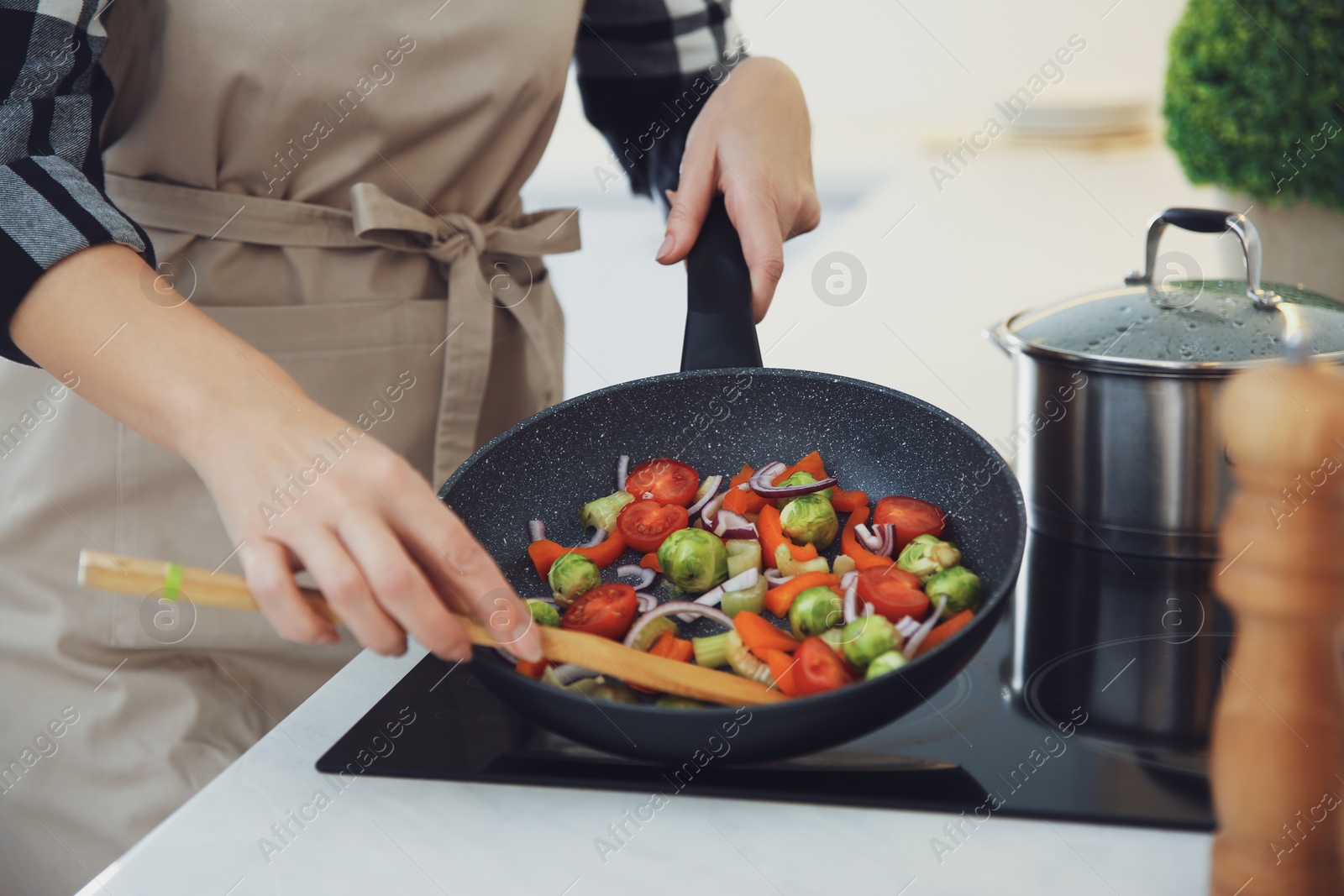 Photo of Woman cooking on stove in kitchen, closeup