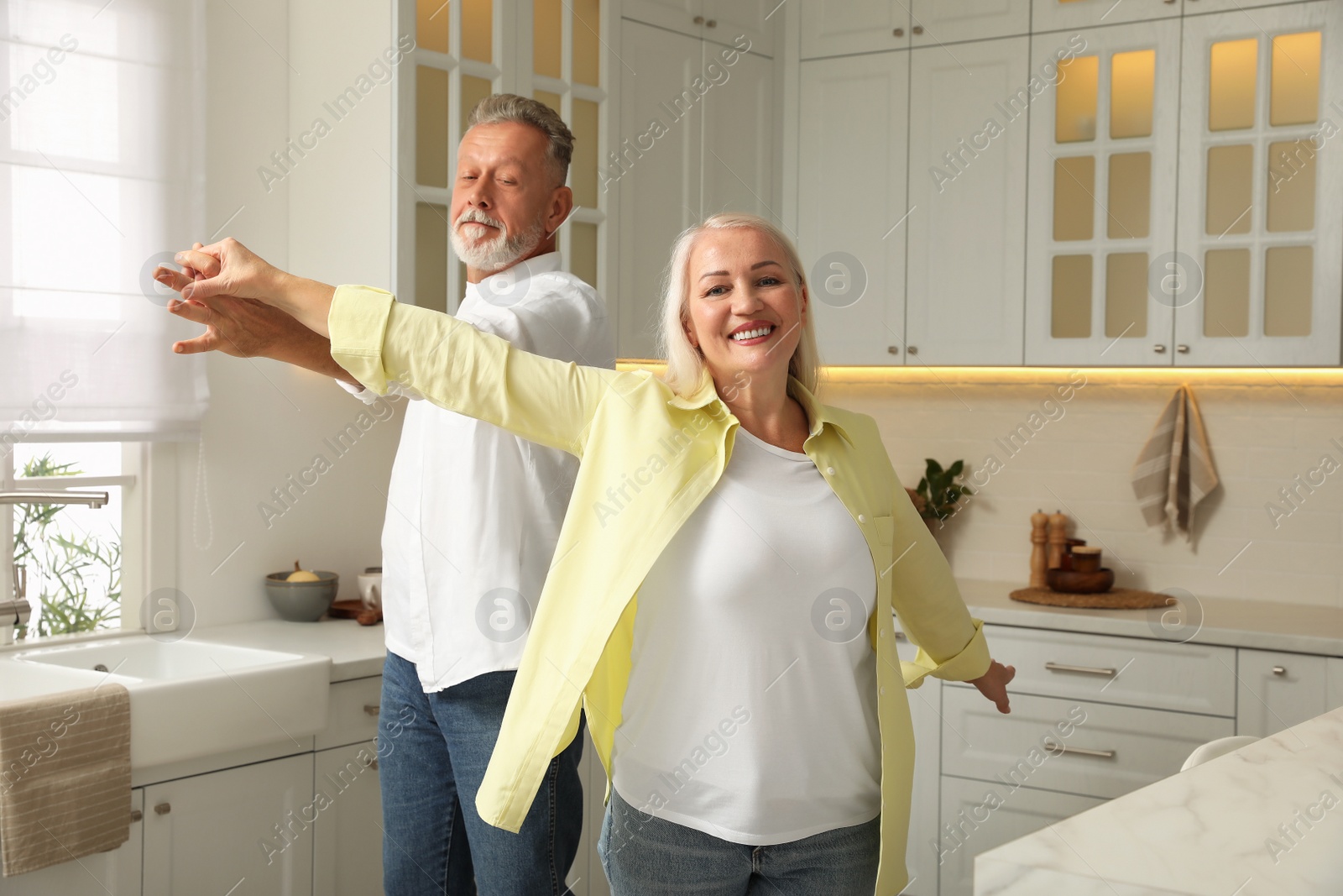 Photo of Happy senior couple dancing together in kitchen