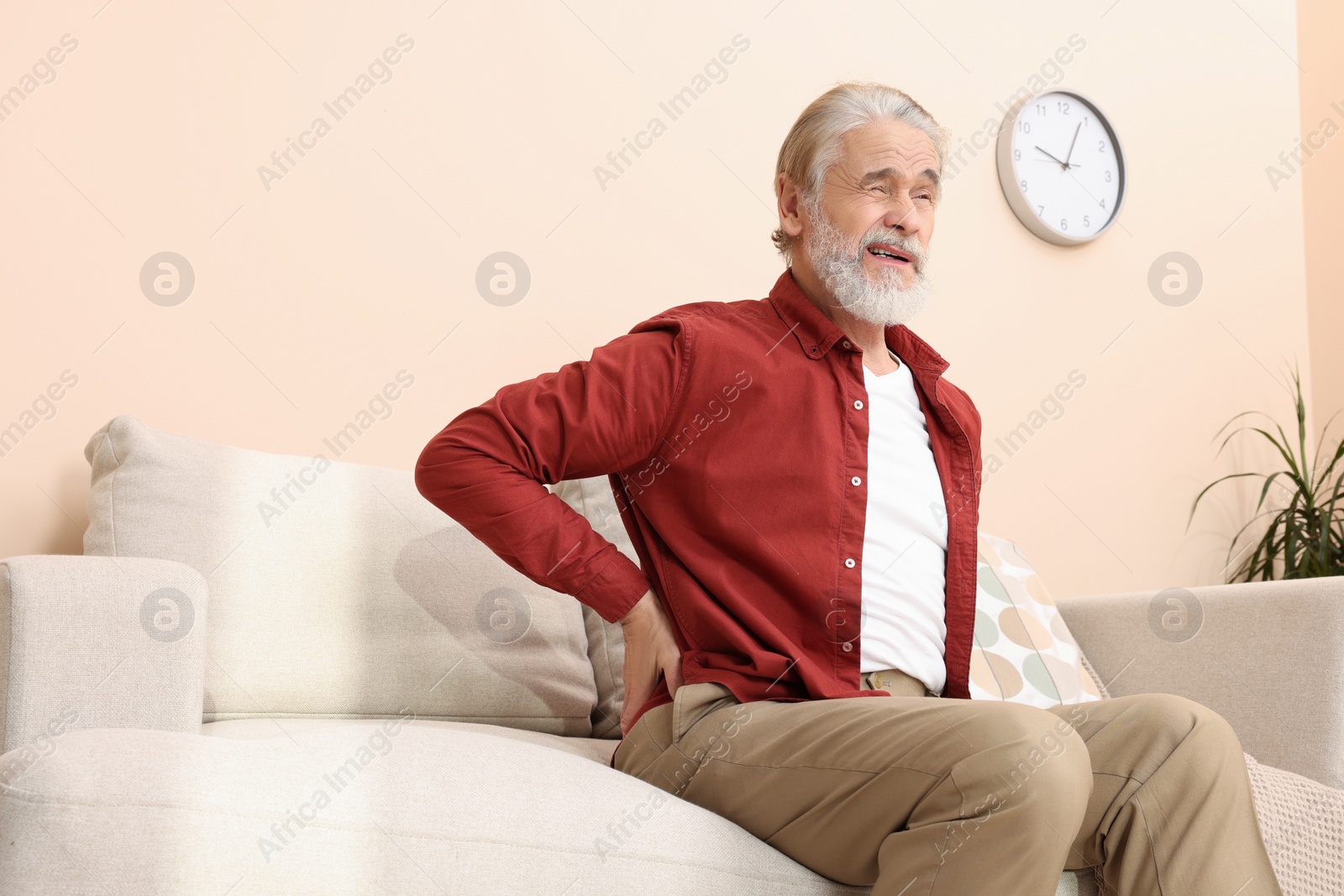 Photo of Senior man suffering from pain in his back at home. Arthritis symptoms