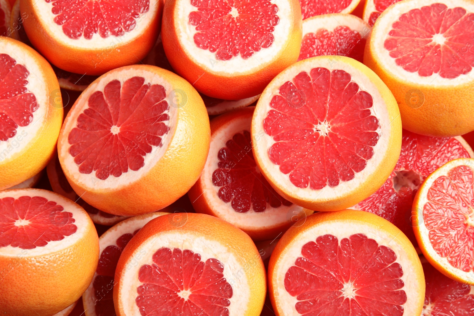 Photo of Many sliced fresh grapefruits as background, top view