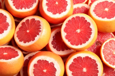 Many sliced fresh grapefruits as background, top view