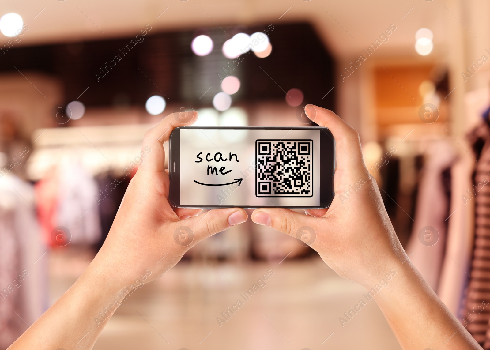 Image of Woman holding smartphone with QR code on screen in store, closeup