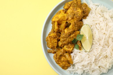 Photo of Delicious chicken curry with rice on yellow background, top view. Space for text