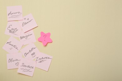 Photo of Choosing baby name. Paper stickers with different names and question mark on beige background, flat lay. Space for text