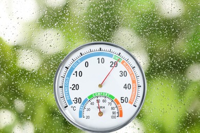 Mechanical hygrometer with thermometer on glass with water drops
