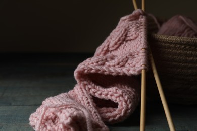 Photo of Pink knitting and needles on wooden table, closeup. Space for text