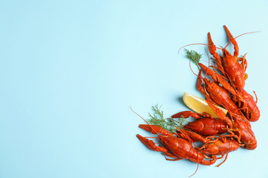 Photo of Delicious boiled crayfishes with lemon and dill on light blue background, flat lay. Space for text